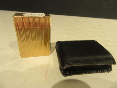 un portefeuille noir et un briquet doré posés sur une table