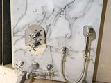 a bathroom with a marble wall and a shower head