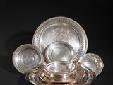 an antique silver plate with a bowl and saucer on a black background