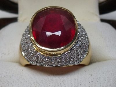 an image of a ring with a red stone surrounded by diamonds