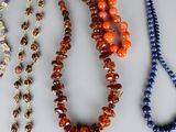 several necklaces of various colors and shapes are displayed on a table