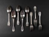 six silver spoons and two silver spoons on a black surface
