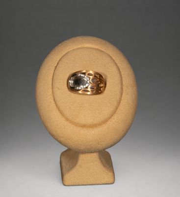 une bague en or sertie d'un diamant, posée sur un socle