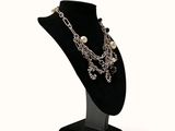 necklace with pearls and chains on a black stand on a white background