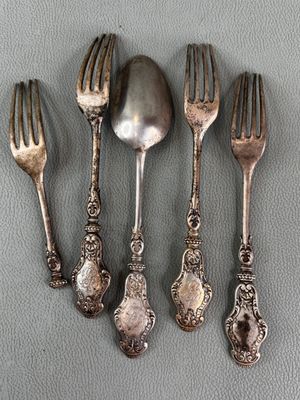 four silver spoons and a fork on a gray surface