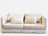 a white couch with pillows on it against a white wall
