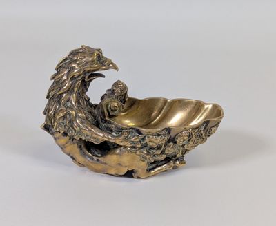 une image représentant une figurine en bronze d'un aigle posé sur un coquillage