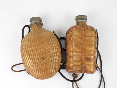 pair of antique wicker water bottles on a white background