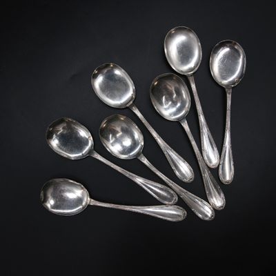 six silver spoons are arranged in a row on a black surface