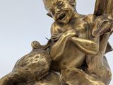 a statue of a boy with a bird on a leaf
