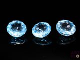 three blue topazte gems sitting on top of a black surface