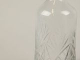 a clear glass bottle with a stopper next to it