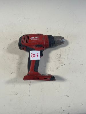 une perceuse sans fil rouge posée sur une surface blanche