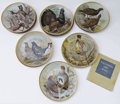 six assiettes sur lesquelles sont peints différents oiseaux, posées sur une table