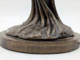 bronze statue of a woman holding a bird on a pedestal