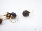 two pairs of gold and black glass earrings on a white surface