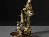 un vase orné de fleurs et d'un oiseau, posé sur une assiette