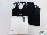 un haut de sport et un legging noir et blanc posés sur une table blanche