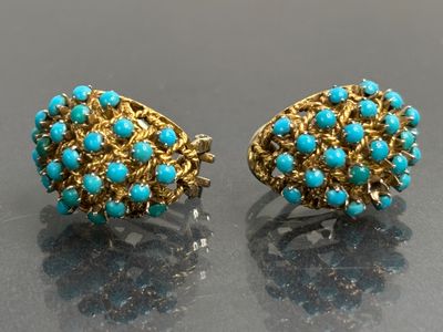 une paire de boucles d'oreilles turquoise et or sur un fond noir