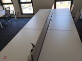 two desks in a room with windows in the background