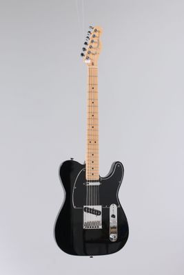 a black electric guitar hanging from a white wall