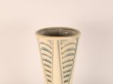 a white vase with a leaf design on it