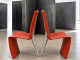 une chaise rouge qui se trouve dans une pièce aux murs en béton