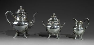 trois théières en argent et une cafetière posées sur une table