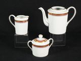 three pieces of white and gold teapots and cups on a black background