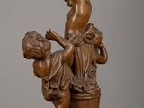 an antique bronze statue of a boy and a girl sitting on a bucket