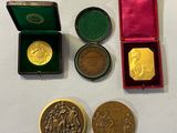 three gold and silver medals in a red box on a white surface