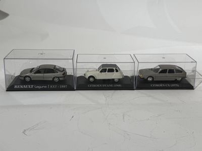 trois voitures miniatures sont exposées dans une vitrine transparente posée sur une surface blanche