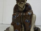 a figurine of a man sitting on a leaf