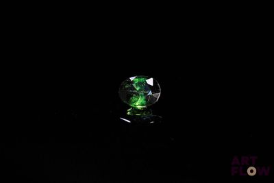 une image représentant un cristal vert posé sur une surface noire