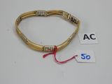gros plan d'un bracelet en or sur une surface blanche