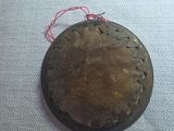 a small metal object on a table with a red string