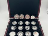 a wooden box with twelve silver coins in it on a white surface