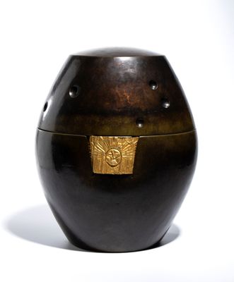 a black vase with a gold lid on a white surface