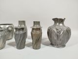three silver vases sitting next to each other on a white surface