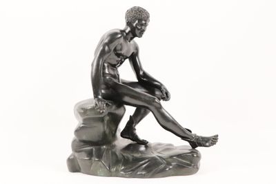 statue of a man sitting on a rock on a white background