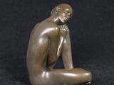 a bronze statue of a man sitting on a black surface