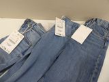two pairs of blue jeans with tags on them sitting on a table