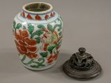 a small vase with a lid sitting next to a smaller vase