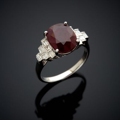 a close up of a ring with a red stone and diamonds