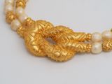 gold plated necklace with pearls and beads on a white surface