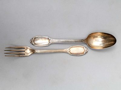 deux cuillères et une fourchette en argent sur une surface blanche