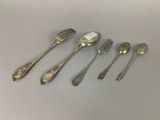 six spoons and a fork are lined up on a table