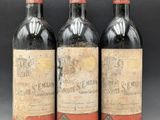 three bottles of red wine sit side by side on a table