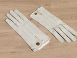 two pairs of white gloves sitting on top of a wooden table