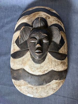 un gros plan d'un masque en bois posé sur un tissu bleu